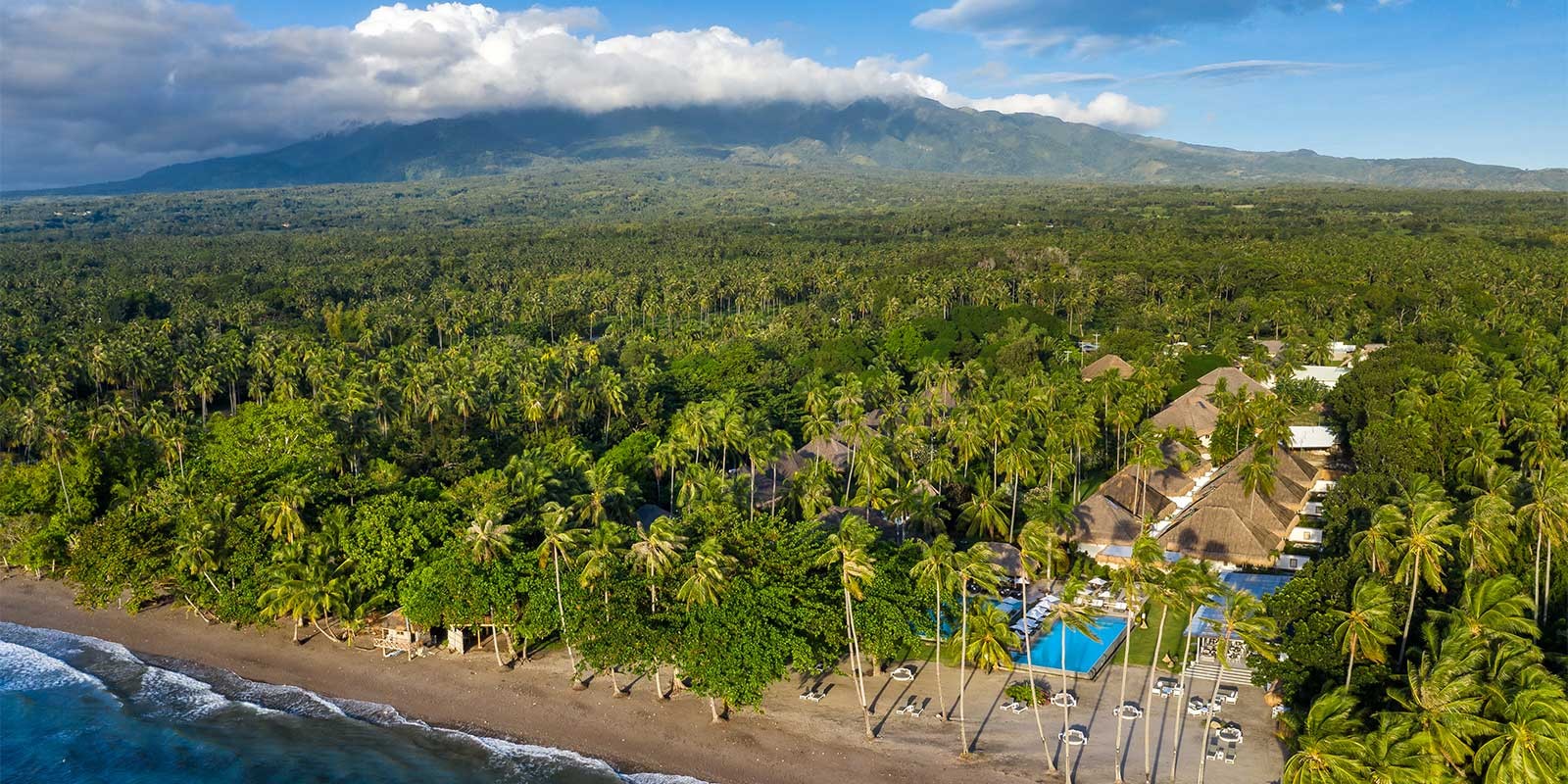 Aerial of Atmosphere Resort & Spa with Mount Talinis in the background. Holiday accommodation in Dauin, Philippines.