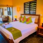 Example of the oceanfront suite at Nasama Resort, with large bed and seating area.