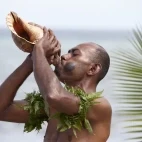 Man blowing conch shell in Fiji.