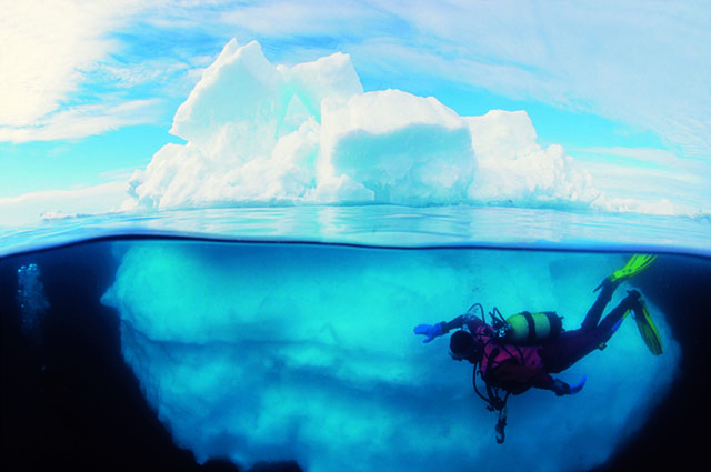 Divers exploring an iceberg in Antarctica.