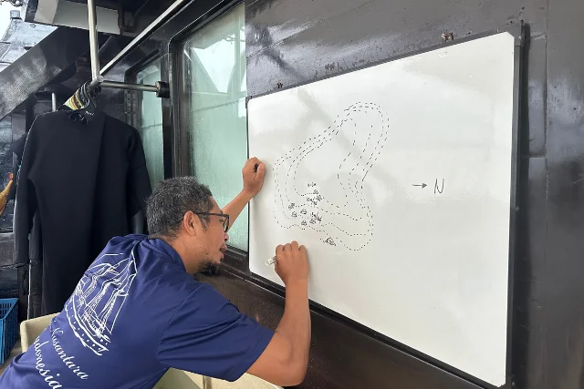 Crew member setting out a map for a dive, on Dewi Nusantara.