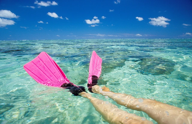 Snorkeller wearing fins and floating in crystal blue water