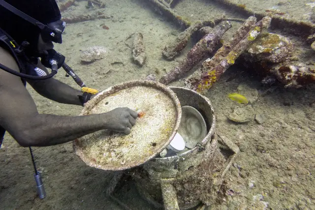 Diver removing a cooking pot lid on the wreck of SS President Coolidge, Vanuatu.